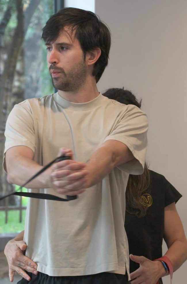 Fisioterapeuta de Clínica Motriz corrigiendo a un paciente durante un ejercicio de fuerza con poleas en la fase de readaptación, en Tres Cantos