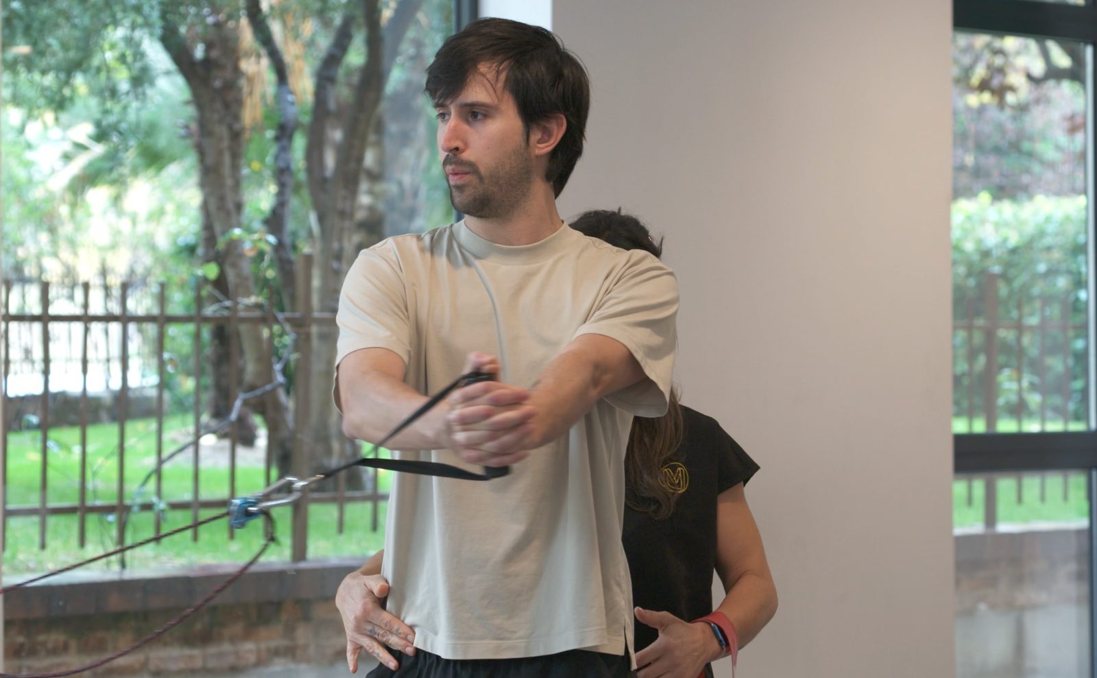 Fisioterapeuta de Clínica Motriz corrigiendo a un paciente durante un ejercicio de fuerza con poleas en la fase de readaptación, en Tres Cantos